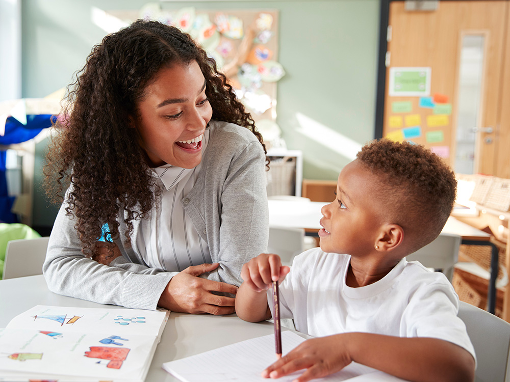 A teacher and a student boy showcasing a joyful moment while drawing together.