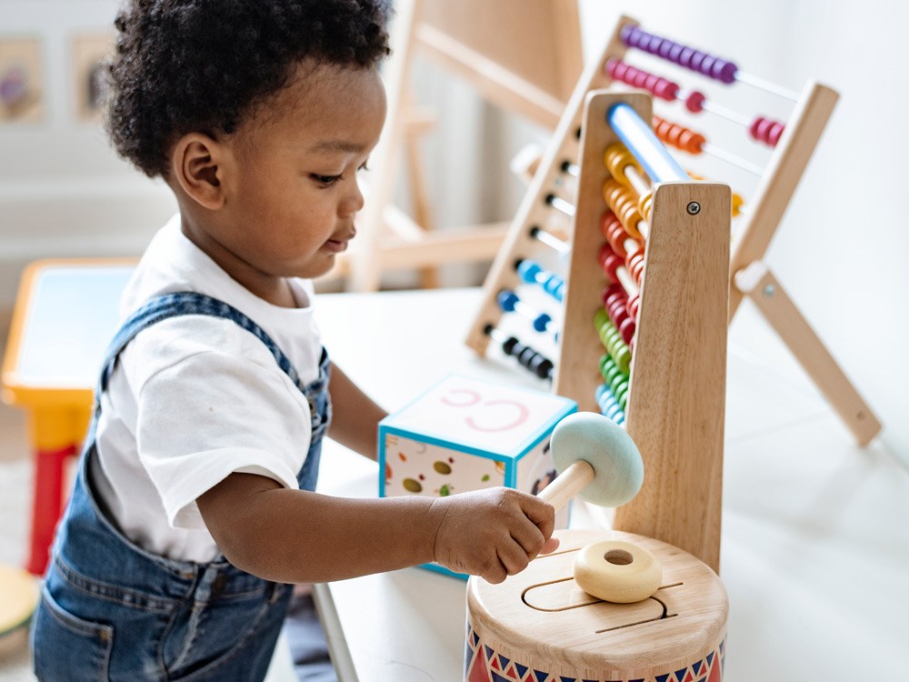 A young child playing with a abacus and stacking toys, focused on the activity.