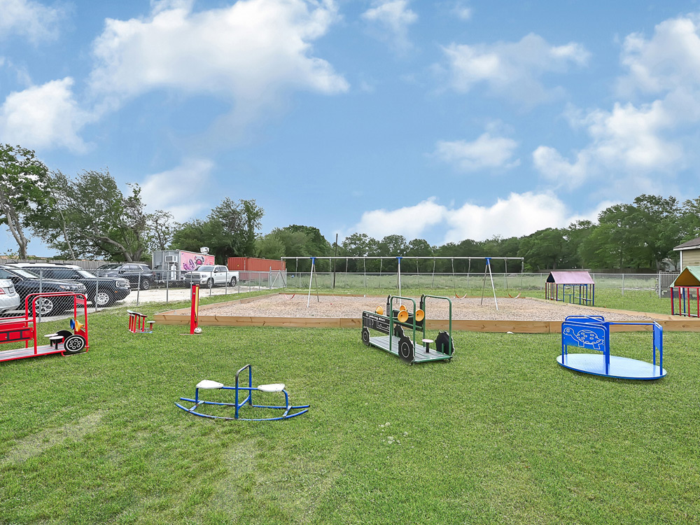 An outdoor playground with equipment on green grass, ready for children to enjoy.