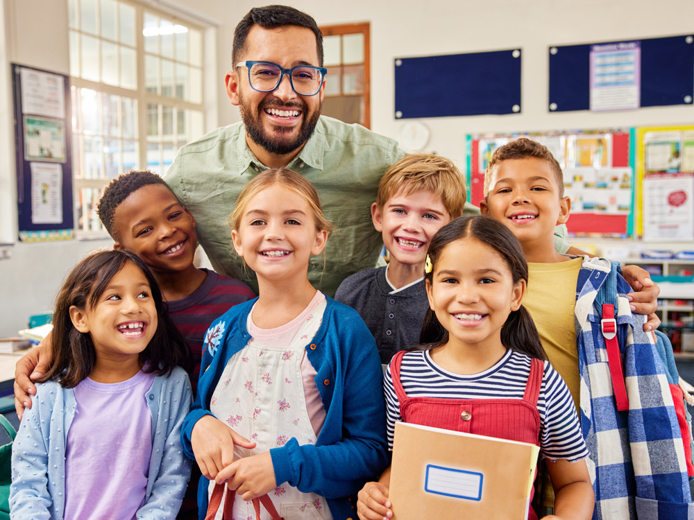 A teacher with six smiling students posing together, all looking happy and engaged.
