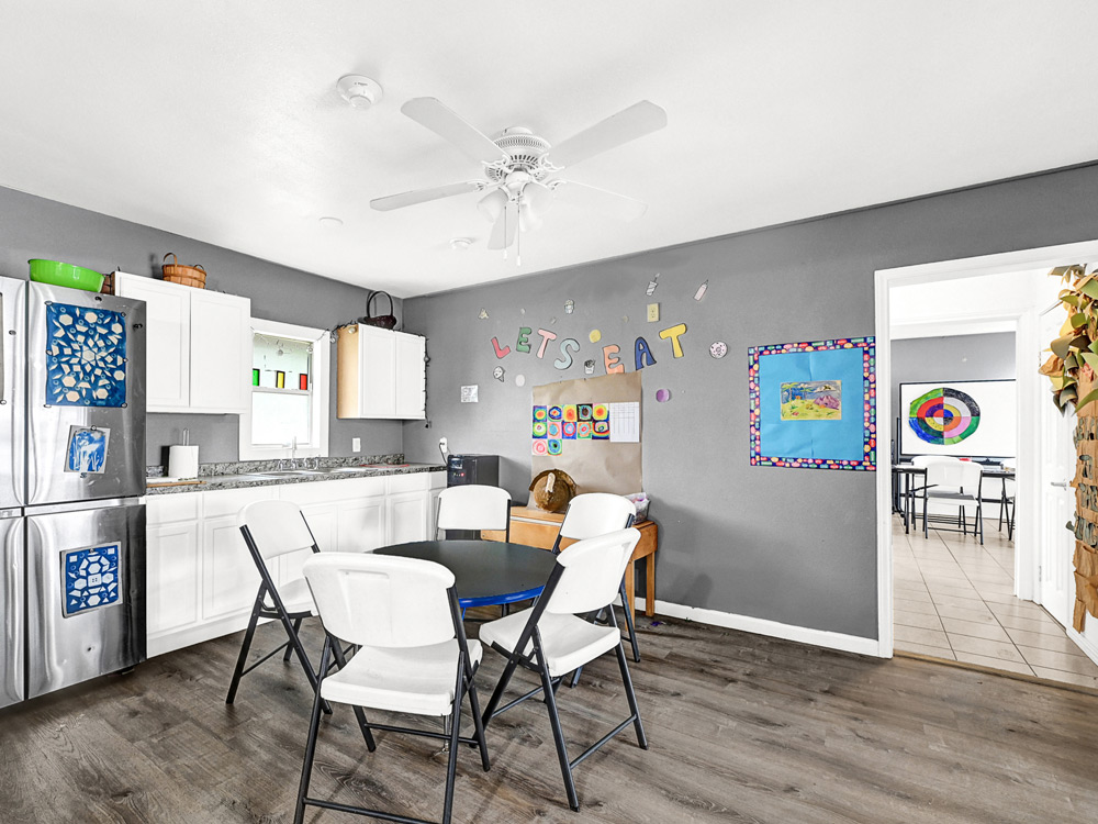 A modern kitchen area with a round table and chairs, featuring a fridge and playful decor.